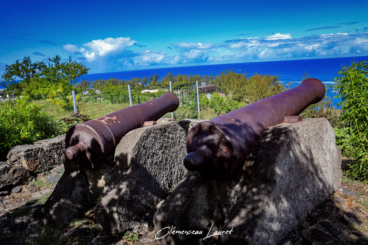 Deux canons historiques en fonte posés sur des socles en pierre face à la mer et sous un ciel nuageux à Saint-Leu.