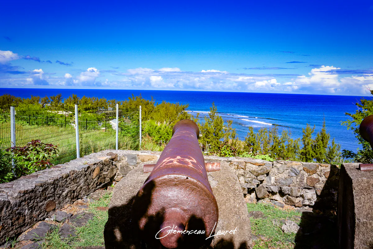 Détail de la tranche de la culasse en métal oxydé d'un canon de la batterie des Sans-Culotte, orienté vers les vagues et la barrière de corail de Saint-Leu.