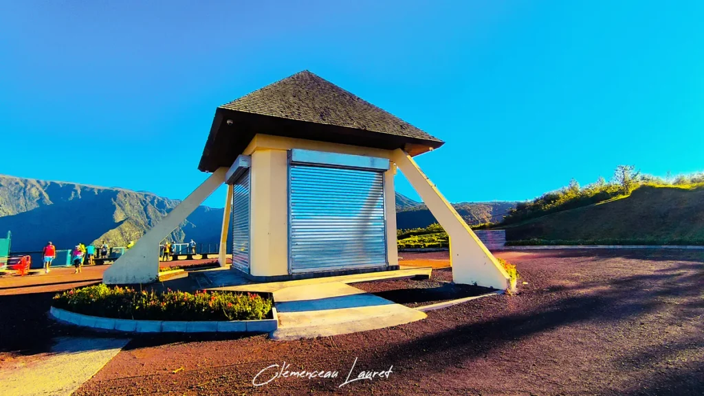 Belvédère de Bois Court à la Réunion avec un toit en bardeaux et des structures métalliques, offrant une vue panoramique sur les montagnes et les randonneurs.