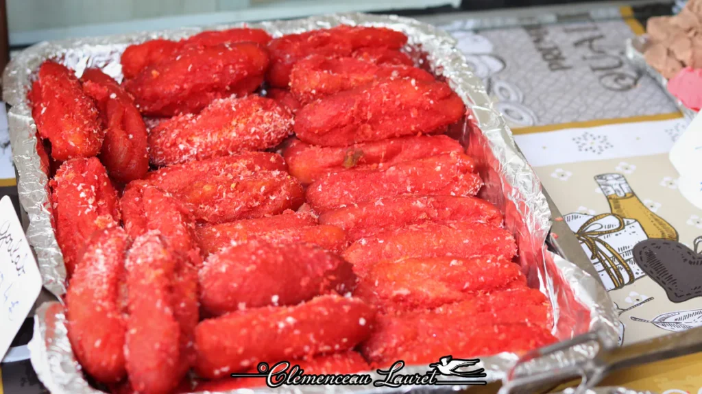 Beignets créoles sucrés d'un rouge éclatant saupoudrés de coco sur un marché réunionnais.