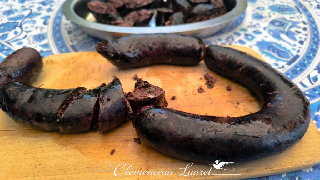 Gros plan sur du boudin créole de La Réunion entier et tranché sur une planche en bois rustique.