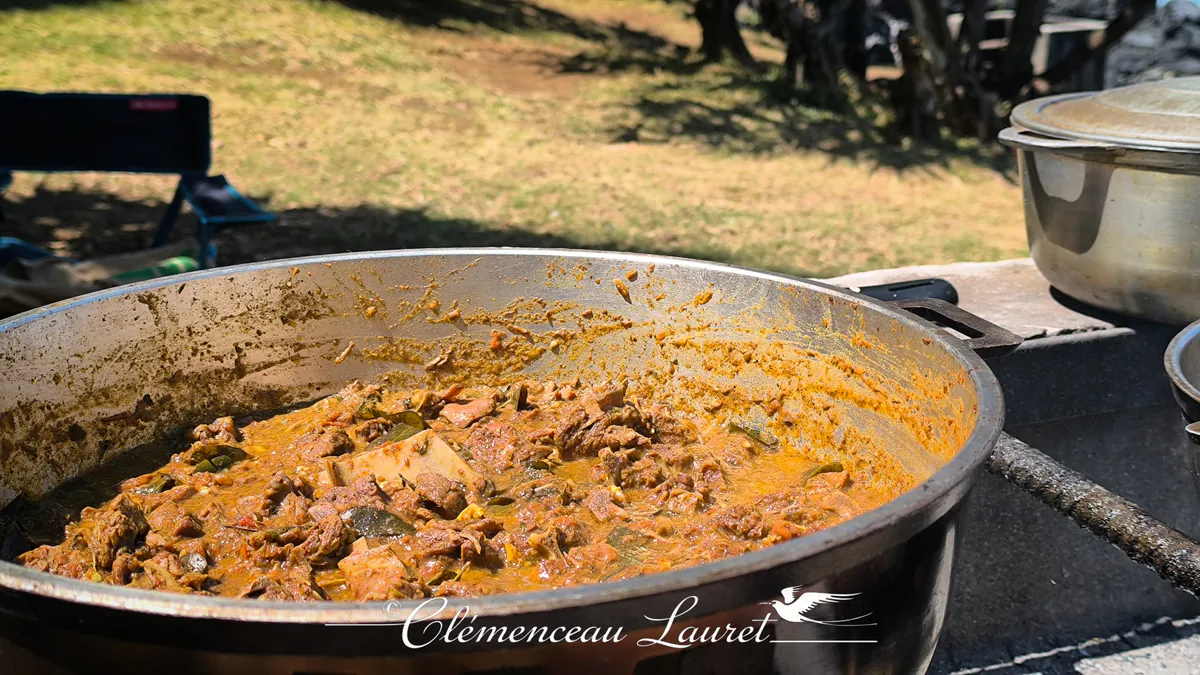 Détail de la sauce onctueuse et des morceaux de viande de cabri mijotés dans une marmite créole.