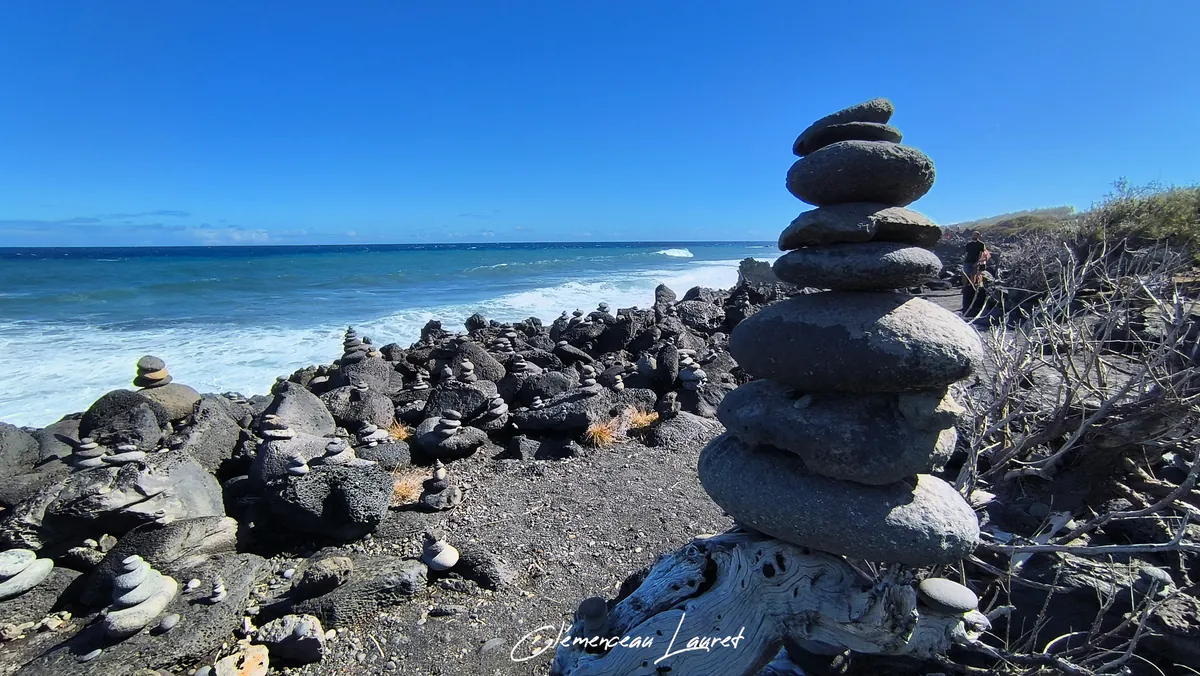 Grand cairn en équilibre au premier plan sur le sentier littoral près du Gouffre