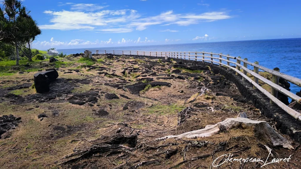 Esplanade rocheuse volcanique sécurisée par une barrière en bois surplombant l'océan au Cap Méchant.