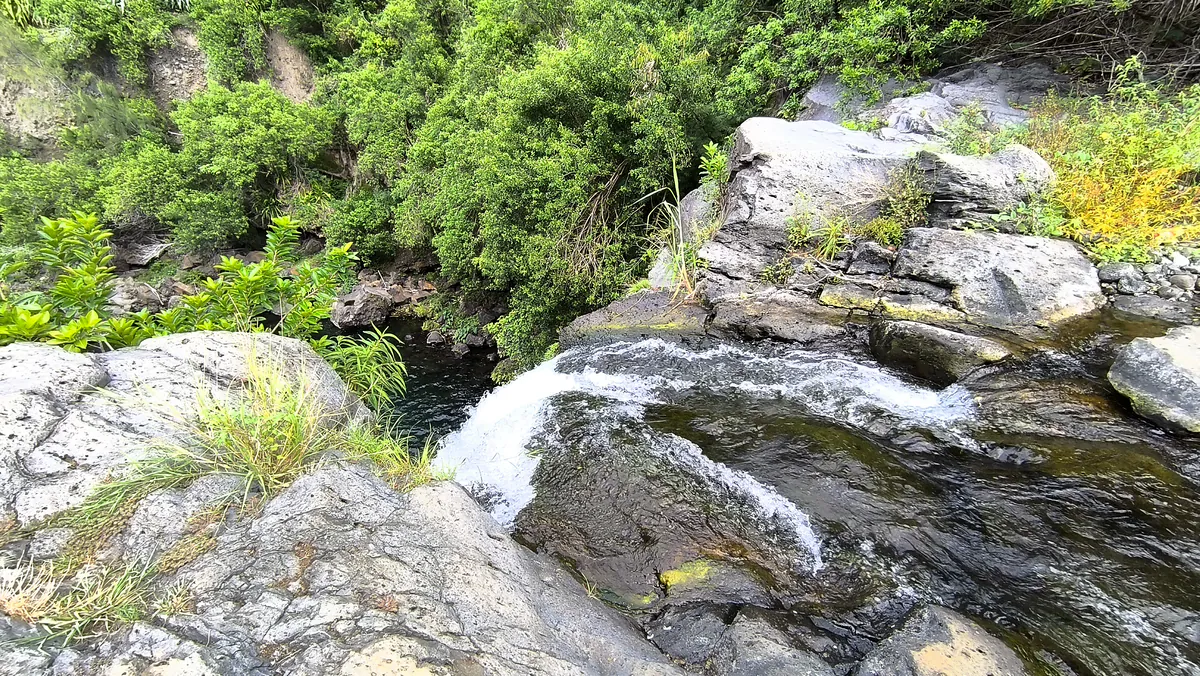 Plan rapproché du courant d'eau vive se déversant sur les rochers en basalte au sommet de la cascade Jacqueline à Saint-Joseph.