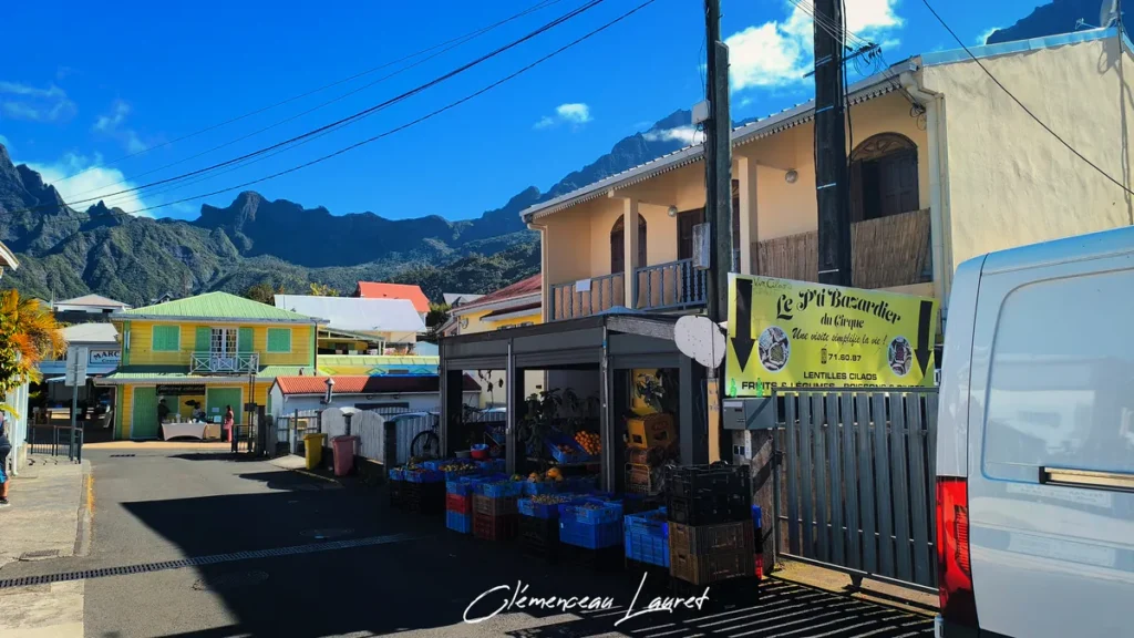 Devanture de l'échoppe Le P'ti Bazardier du Cirque étalant des fruits et légumes en cagettes au bord d'une rue du village de Cilaos.