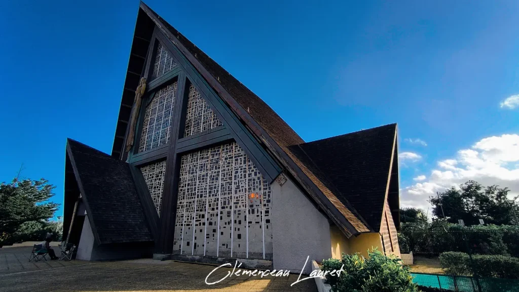 Vue de trois-quarts de l'architecture triangulaire de l'église du Bon Pasteur à Saint-Pierre sous un ciel bleu.