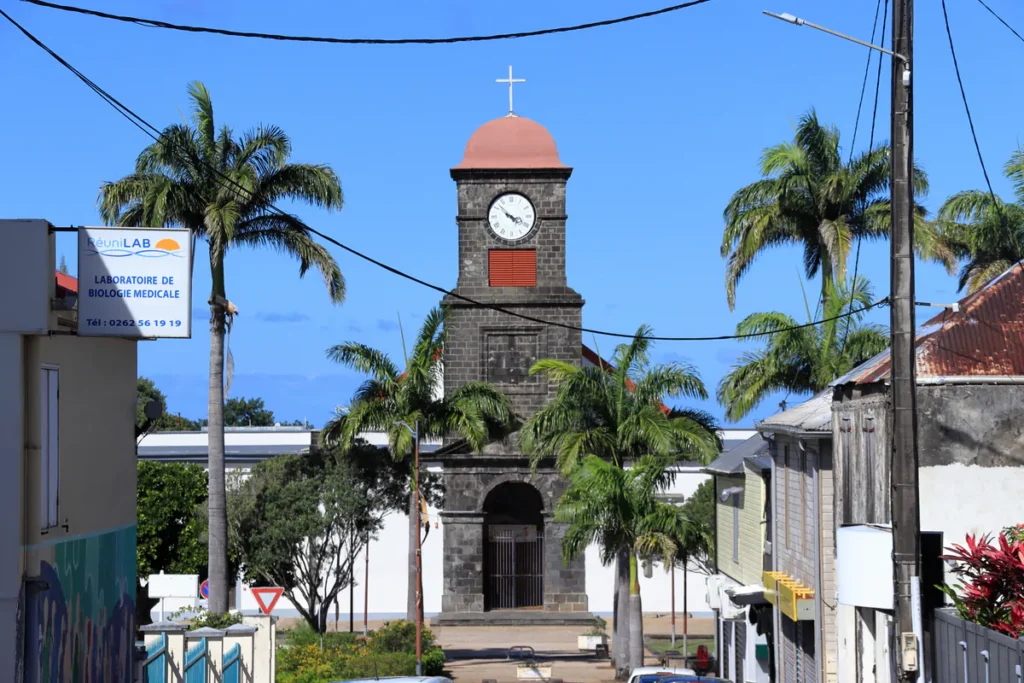 Façade et clocher en pierre de taille de l'église Saint-Joseph à La Réunion encadrés par des palmiers