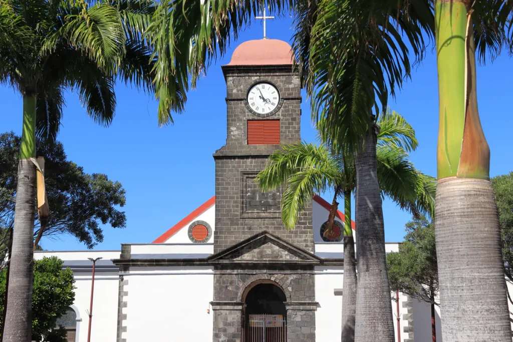Clocher de l'église Saint-Joseph à La Réunion vu de face derrière les troncs de palmiers