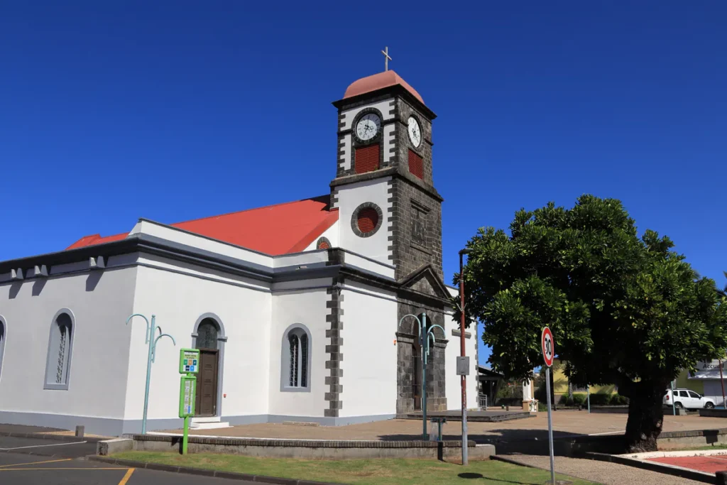 Architecture extérieure de l'église Saint-Joseph à La Réunion avec murs blancs et toit rouge sous un ciel bleu