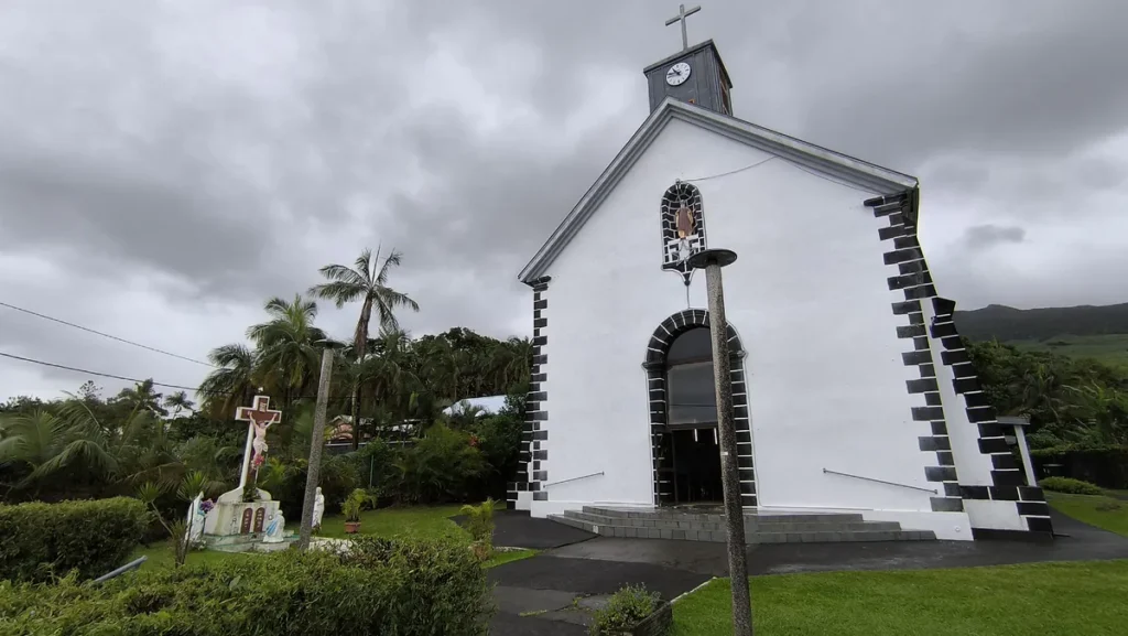 Vue en contre-plongée de l'église Saint-Philippe à blanc et noir avec un calvaire sur la gauche