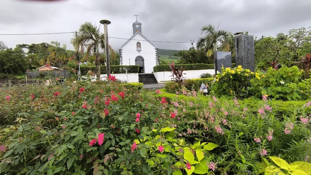 Massif de rosiers roses et de fleurs jaunes au premier plan avec le clocher de l'église Saint-Philippe en arrière-plan	Composition florale mettant en valeur l'église Saint-Philippe depuis le jardin public de