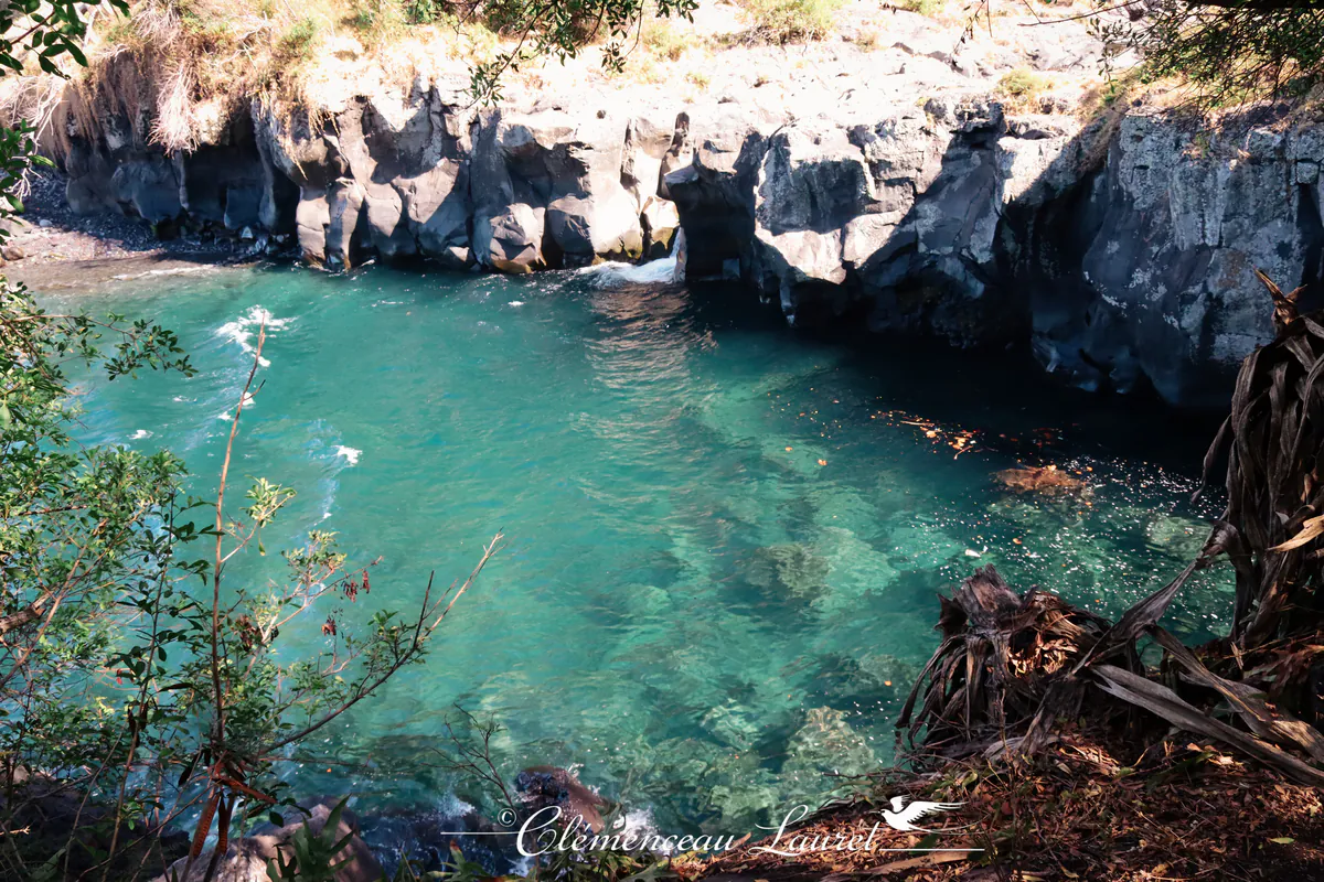 Plongée sur un bassin d eau turquoise tres limpide laissant apparaitre les rochers immerges le long de falaises rocheuses.