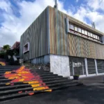 Angle du bâtiment au revêtement en lattes de bois colorées et escalier décoré d'une fresque de lave