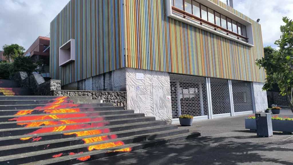 Gros plan sur les marches en pierre peintes d'une coulée de lave rouge et jaune au pied du bâtiment