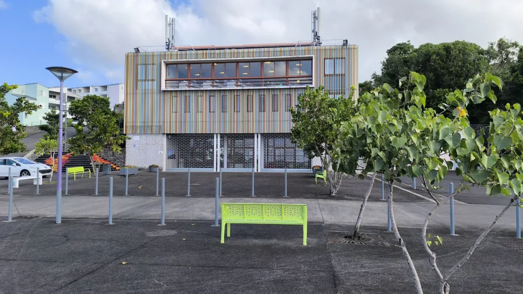 Place publique aménagée avec banc vert et arbres devant l'Espace Citoyen du Livre et des Arts