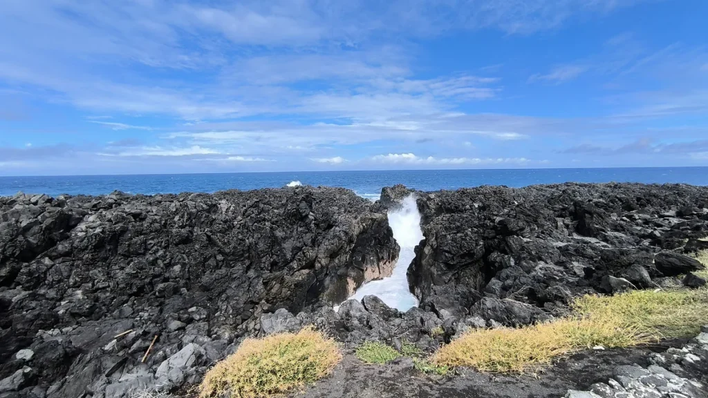 Écumante gerbe d'eau jaillissant de la faille rocheuse du Gouffre de l'Étang-Salé.