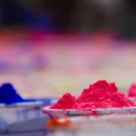 Coupelles remplies de poudres de pigments rose fluo et bleu vif posées en rangée pour la fête de Holi.
