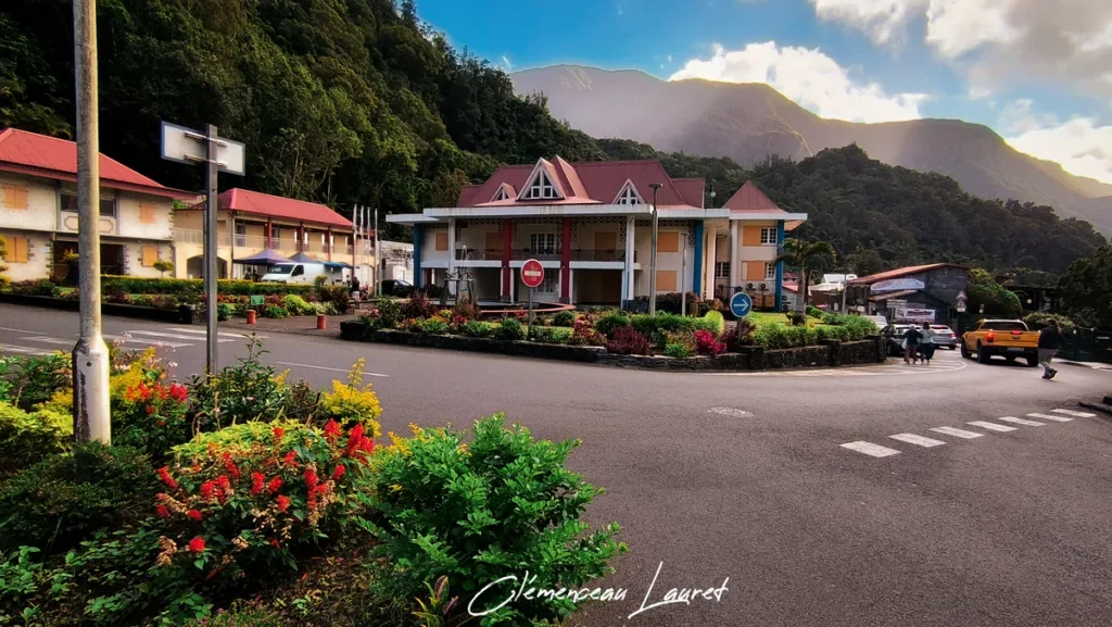 Vue d'ensemble de la rue, des massifs de fleurs et de la mairie de Salazie au pied des montagnes