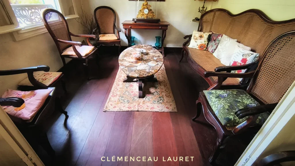Salon d'époque avec fauteuils en canné, table en marbre et parquet en bois sombre