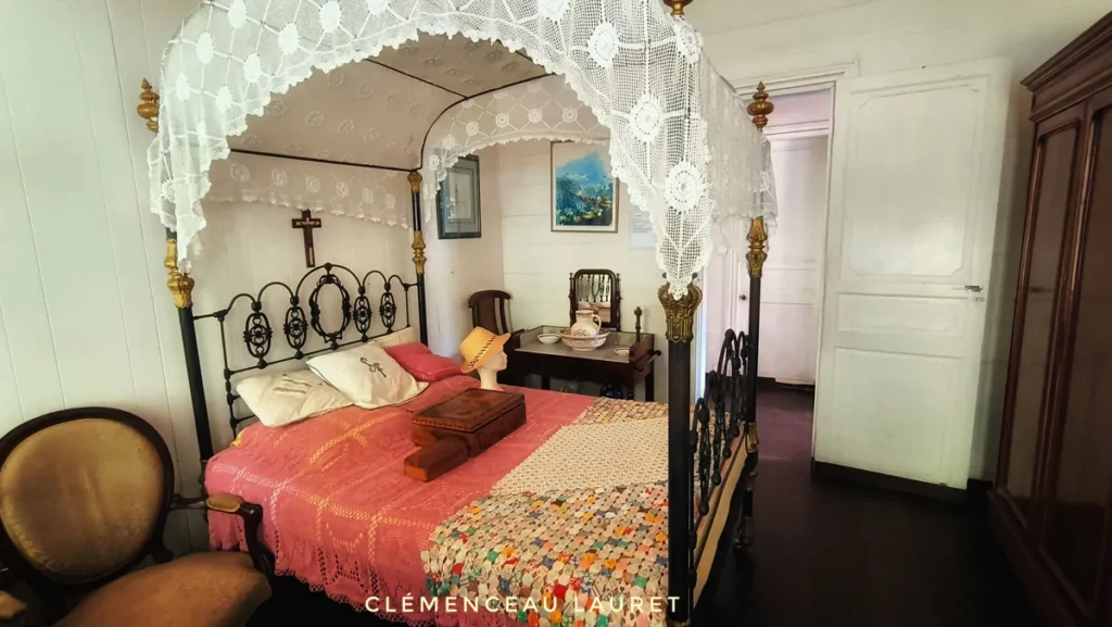 Chambre traditionnelle avec lit à baldaquin en fer forgé, dentelle blanche et couvre-lit rose