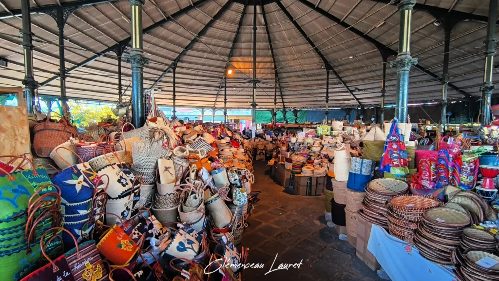 Étalage de cabas colorés à motifs fleurs, chapeaux en paille et djinns en vannerie au marché de Saint-Pierre.