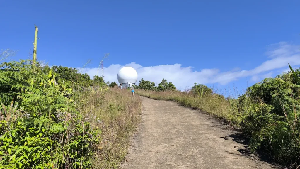 Sentier goudronné en montée menant vers le radôme blanc du radar météorologique sous un ciel bleu au Parc du Colorado.