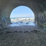 Vue de l'océan Indien à travers un tunnel voûté en béton couvert de graffitis à la Ravine des Colimaçons, Saint-Leu.