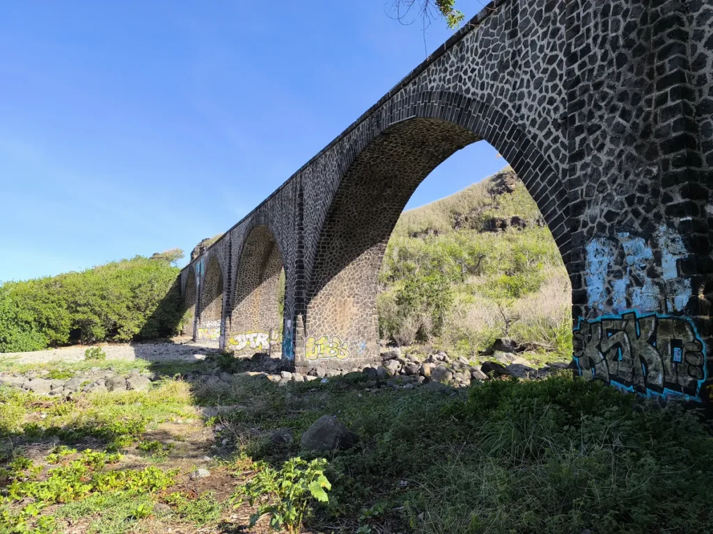 Perspective des arches du viaduc en pierre bordé par la végétation à la Ravine des Colimaçons, Saint-Leu.