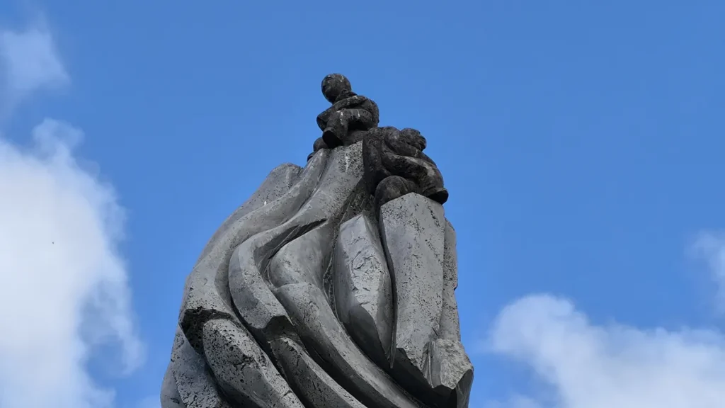 Gros plan sur le sommet sculpté de l'œuvre montrant deux personnages en basalte.