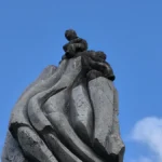 Gros plan sur le sommet sculpté de l'œuvre montrant deux personnages en basalte.