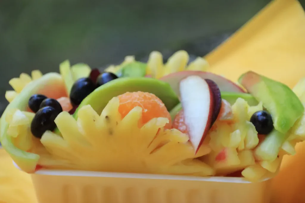 Gros plan sur les détails de la chair d'ananas sculptée et des baies pimentées dans une barquette à Saint-Gilles, La Réunion.