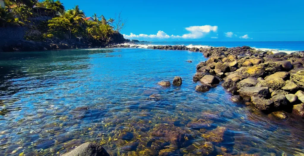 Eau limpide révélant les galets fondateurs du bassin sous une lumière vive à Manapany à Saint-Joseph.
