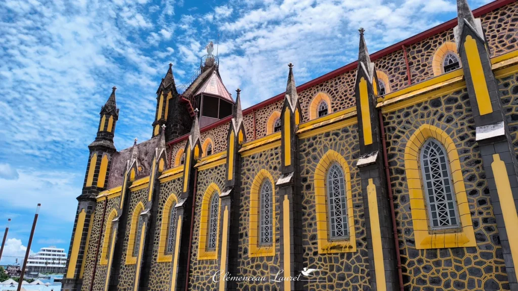 Gros plan sur les détails architecturaux et les hautes fenêtres en arc brisé de la façade latérale de l'église Notre-Dame de la Délivrance, à Saint-Denis, La Réunion — Photo : Clémenceau Lauret (CC BY-SA 4.0).