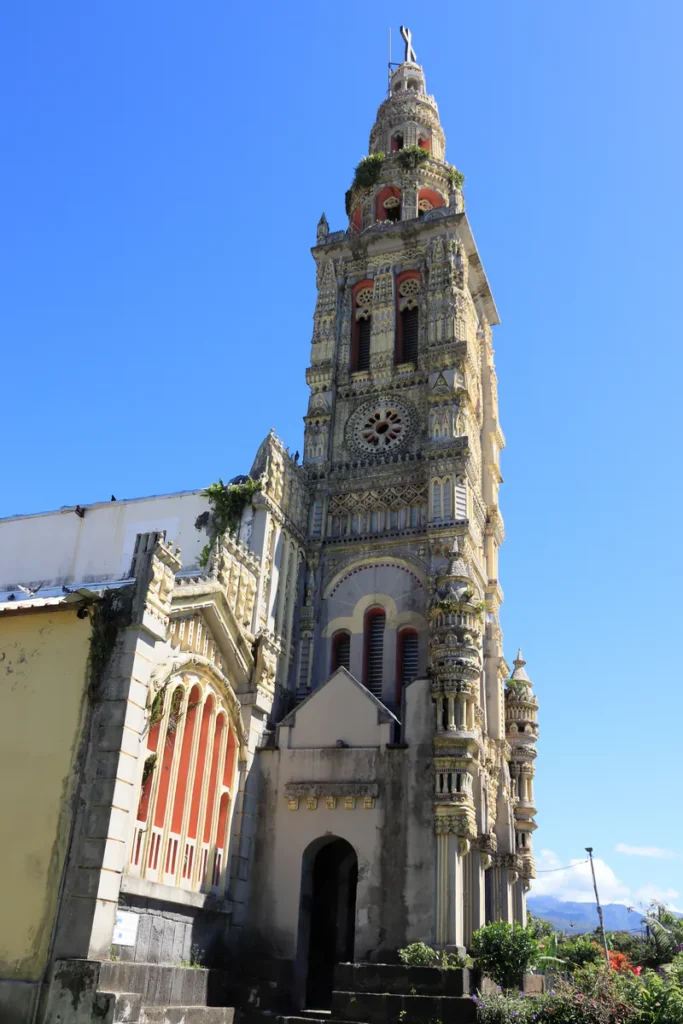 Façade sculptée et clocher ornés de l'église Sainte-Anne à Saint-Benoît sous un ciel bleu ensoleillé.