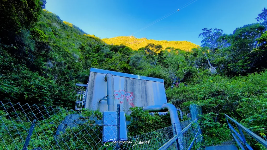 Station de pompage hydraulique en contrebas d'un rempart baigné par la lumière du soleil couchant à Grand Bassin.