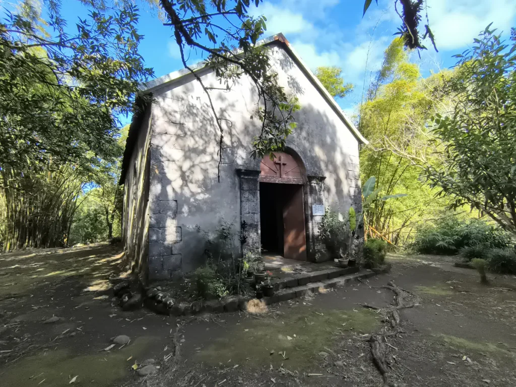 Façade en pierre de basalte de la chapelle de l'Îlet Bethléem à Saint-Benoît sous un ciel bleu dégagé.