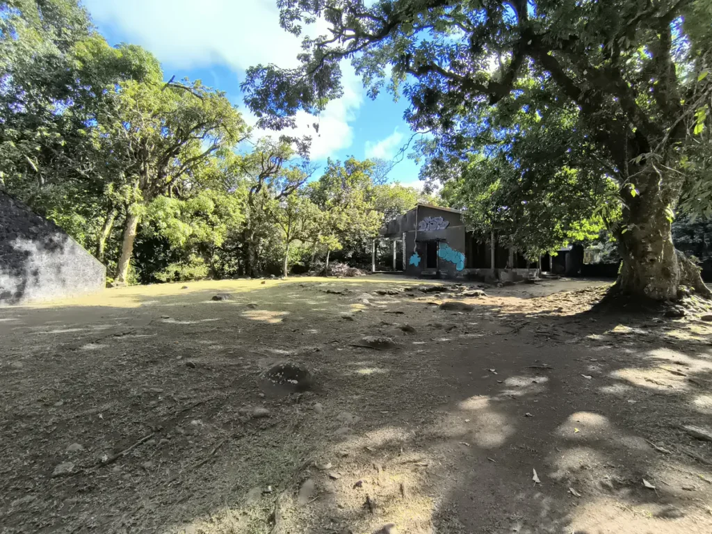 Grande esplanade ombragée bordée par un édifice ancien et de grands arbres à l'Îlet Bethléem