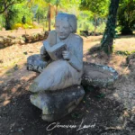 Statue en pierre taillée d'une femme lisant le Code Noir assise dans le jardin à Saint-Paul.