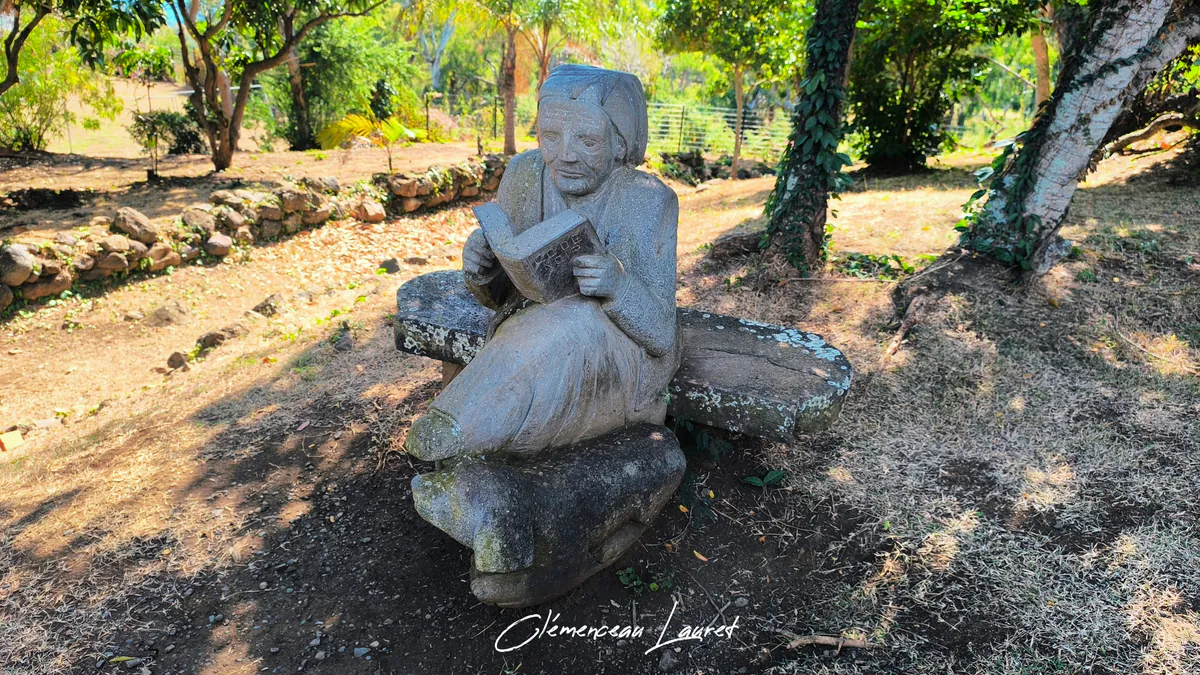 Statue en pierre taillée d'une femme lisant le Code Noir assise dans le jardin à Saint-Paul.