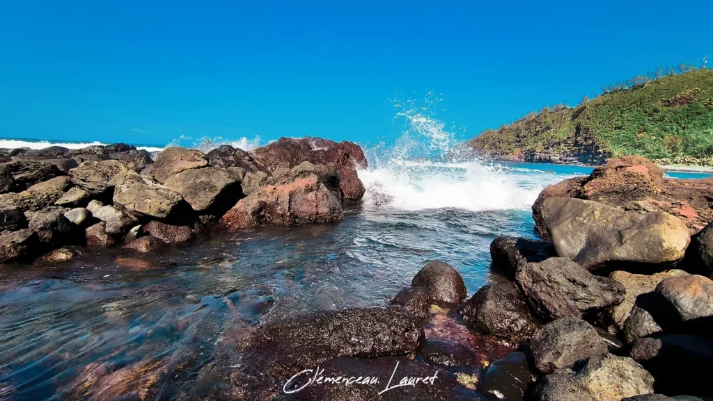 Éclat d'eau sous une vague se brisant violemment contre la digue de roches basaltiques du bassin de Manapany-les-Bains.