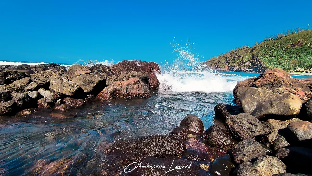 Éclat d'eau sous une vague se brisant violemment contre la digue de roches basaltiques du bassin de Manapany-les-Bains.