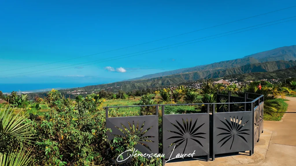 Panorama sur la côte et les montagnes verdoyantes depuis le belvédère avec rambarde décorée au Parc des Palmiers à Le Tampon, Île de La Réunion. Photo : Clémenceau Lauret (CC BY-SA 4.0).