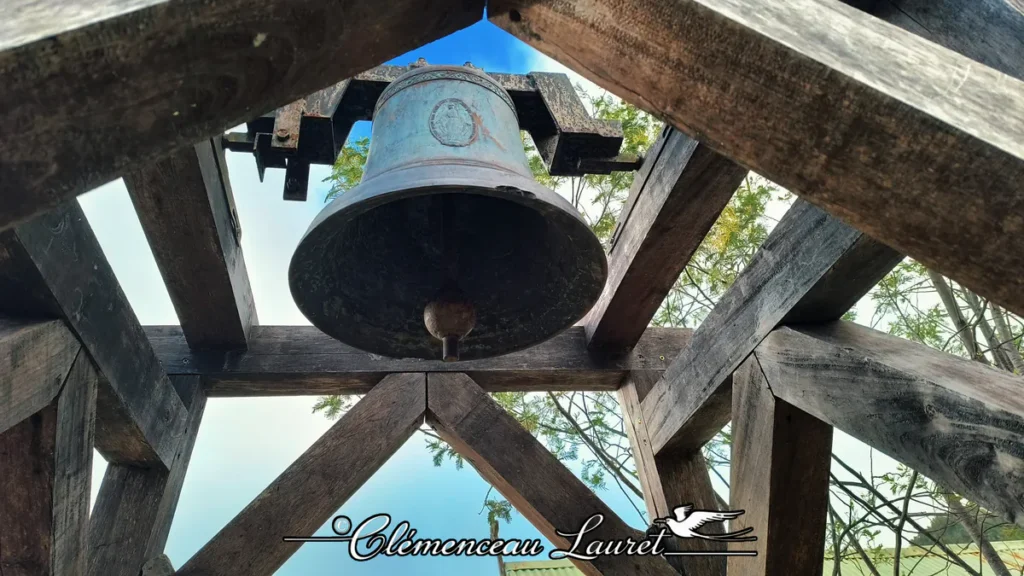 Gros plan en contre-plongée sur la cloche en bronze suspendue dans une structure en bois, à la chapelle de Marla à La Réunion.