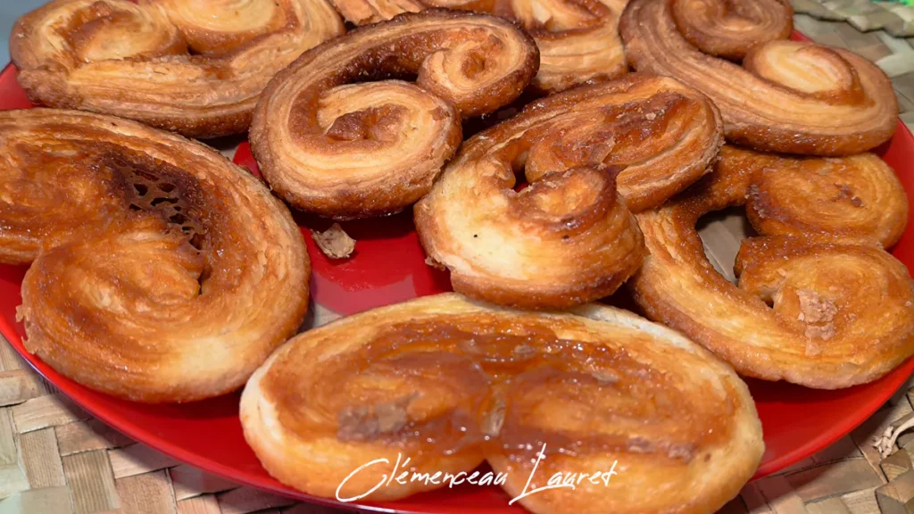 Vue rapprochée sous un éclairage chaud mettant en valeur la texture croustillante et l'enrobage de sucre caramélisé d'un assortiment de palmiers feuilletés faits maison à Saint-Joseph, La Réunion. Prise de vue et photographie réalisées par Clémenceau Lauret.