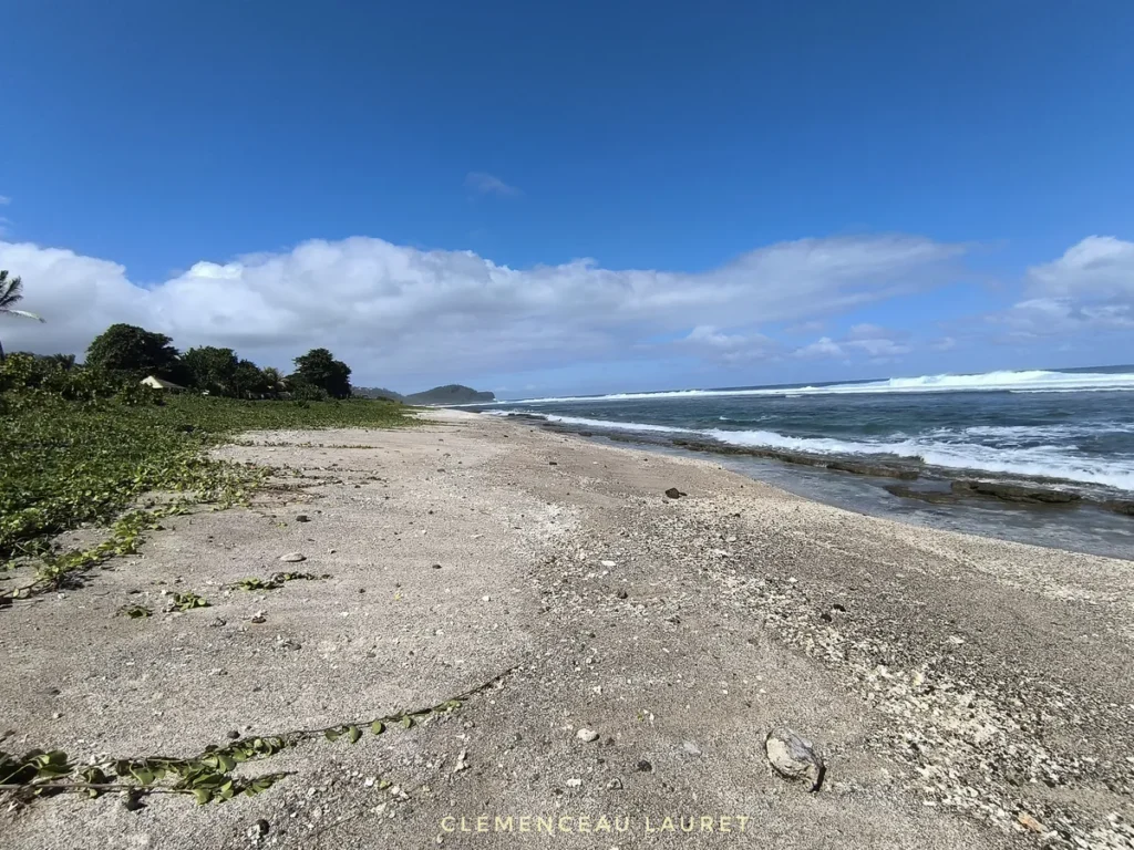 Grande étendue de sable corallien et vagues de l'océan Indien à la plage de Grand Bois à Saint-Pierre sous un ciel dégagé