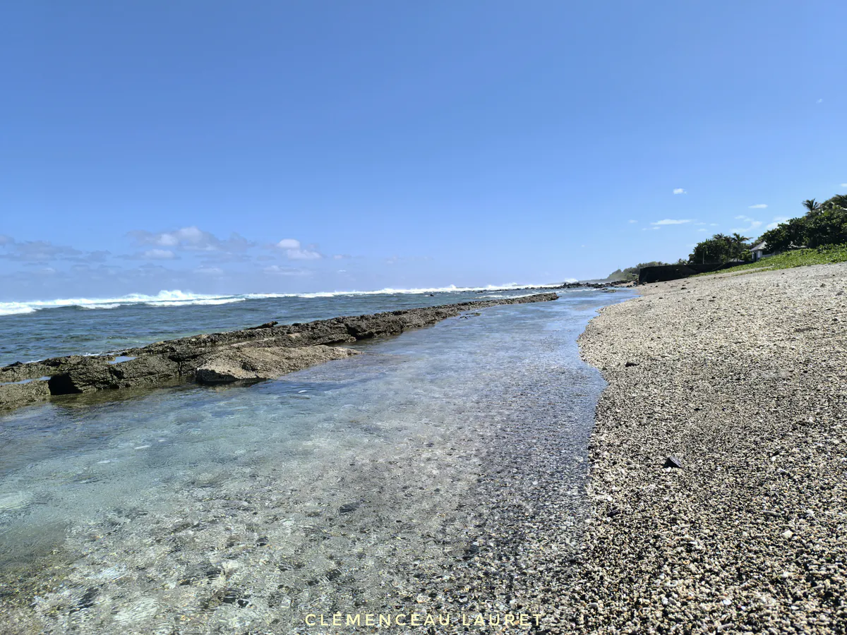 Eau cristalline bordant le platier rocheux et la plage de sable à Grand Bois Saint-Pierre sous un grand soleil