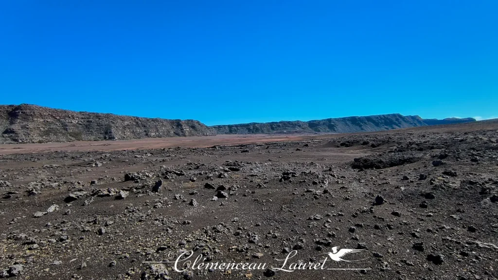 Immensité du plateau volcanique de la Plaine des Sables constellé de petites pierres et bordé par les remparts escarpés à La Réunion, Clémenceau Lauret, CC BY-SA 4.0.