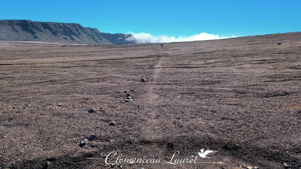 Piste en terre traversant les étendues désertiques et volcaniques de la Plaine des Sables sous une ligne d'horizon dégagée à La Réunion, Clémenceau Lauret, CC BY-SA 4.0.