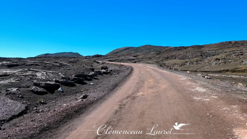 Piste menant vers les hauteurs volcaniques de la Plaine des Sables sous un ciel azur dégagé à La Réunion, Clémenceau Lauret, CC BY-SA 4.0.